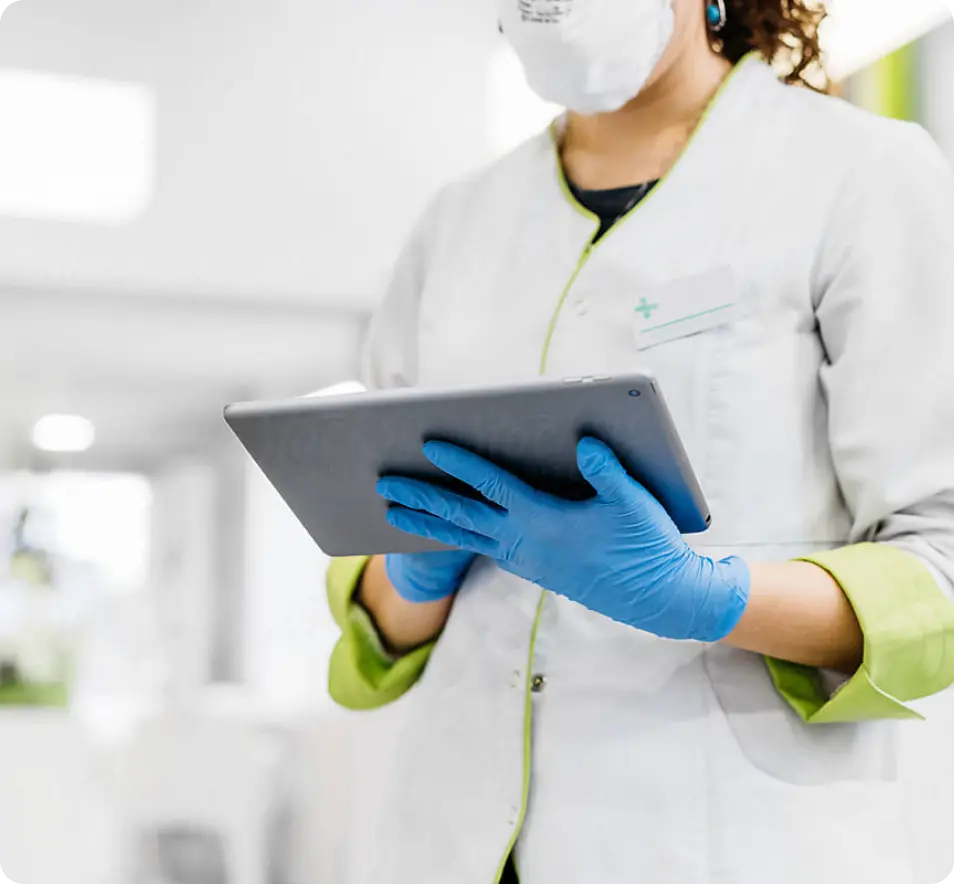 A woman wearing a mask and gloves holding a tablet.