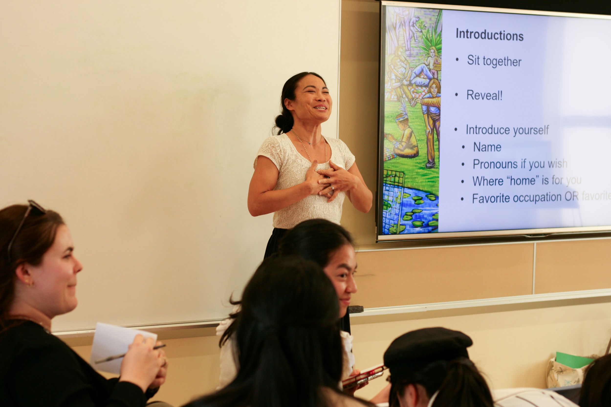 Dr. Ashley Uyeshiro Simon standing at the front of a lecture hall with her hands over her chest