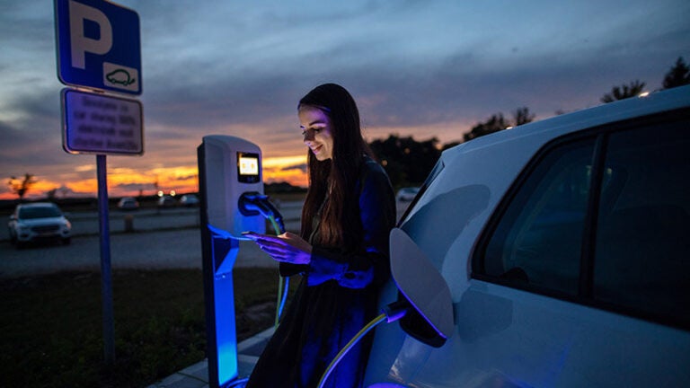 woman charging her electric vehicle at dusk