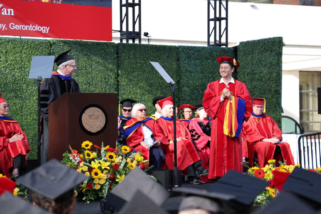 Associate Professor John Walsh introduces PhD graduate Mengzhao Yan during the USC Leonard Davis School Commencement ceremony on May 15, 2026.