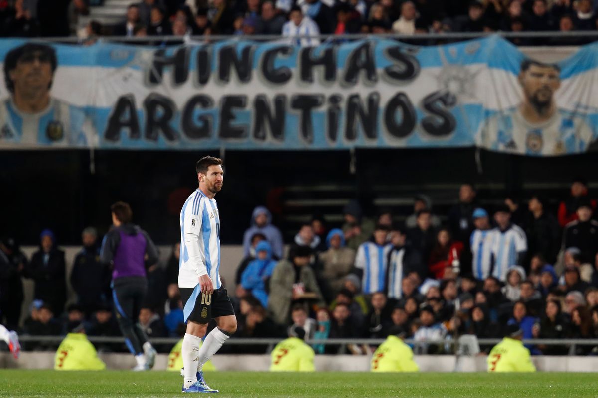 Lionel Messi of Argentina looks on with a banner depicting his and Diego Maradona's faces in the background