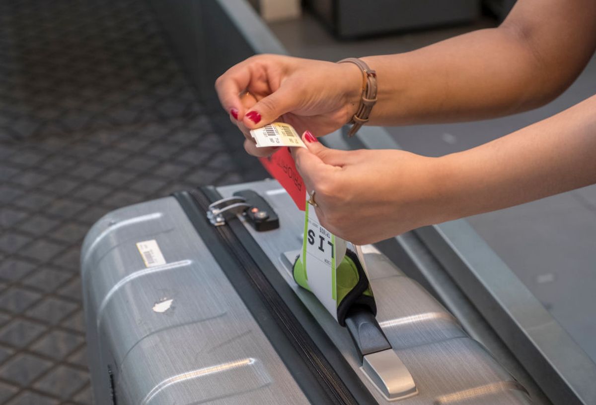 A TAP Air Portugal employee attaches a baggage label to a piece of luggage