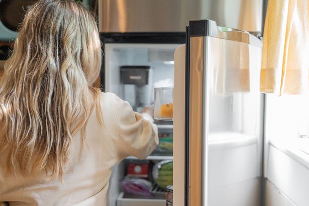 woman looking in open fridge