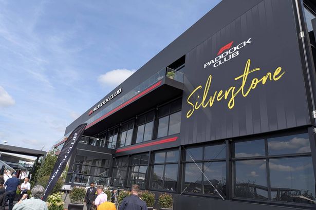 An image depicts a modern architectural structure with a sleek, black exterior and large glass windows. The word "Silhouette" is prominently displayed in bold, yellow text on the building's facade, with a red accent line running through it. Several individuals are gathered in front of the building, suggesting a public event or gathering. The sky above is clear with scattered clouds.