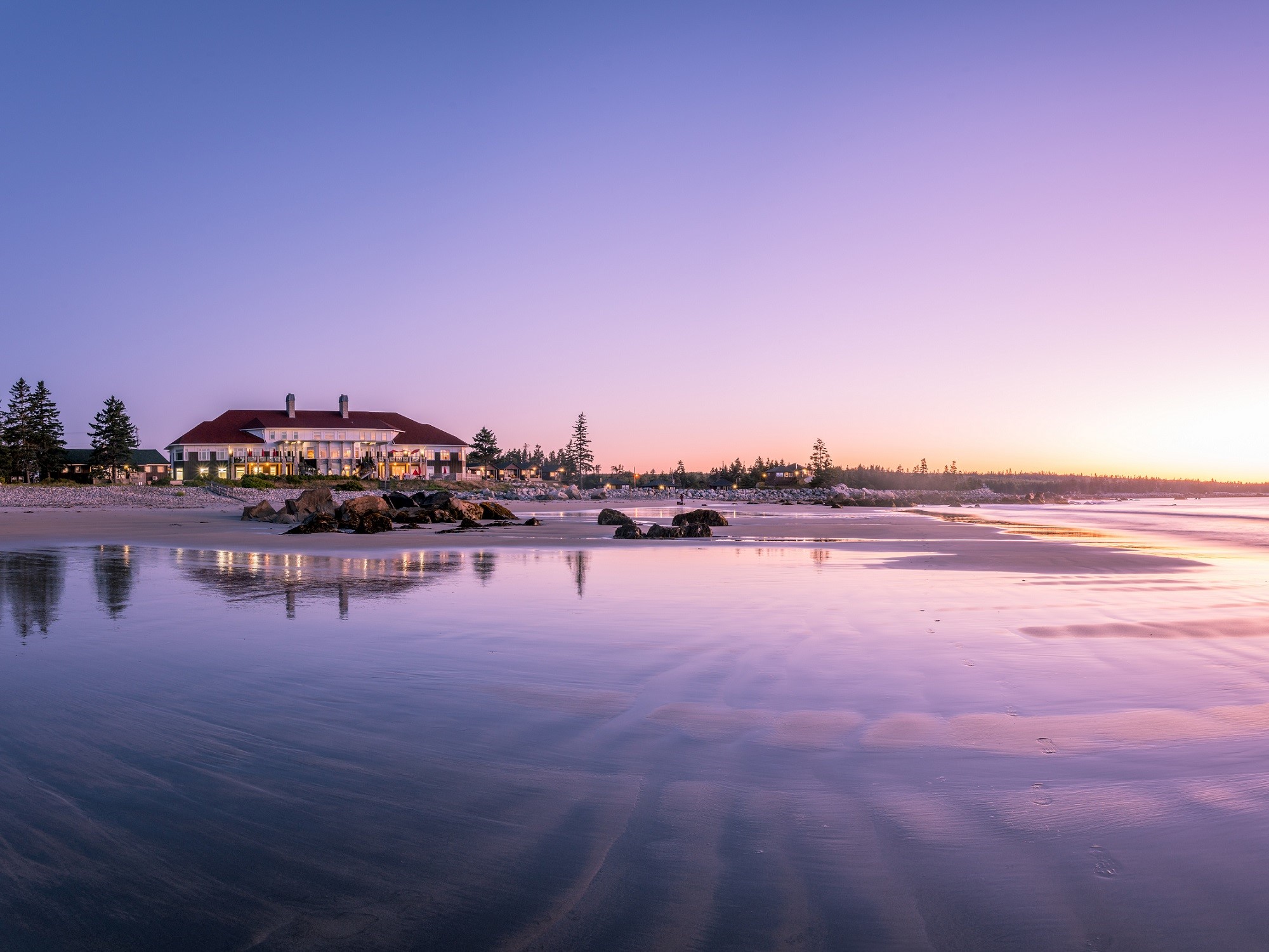 A seaside resort at sunset with purple skies reflected on the beach.