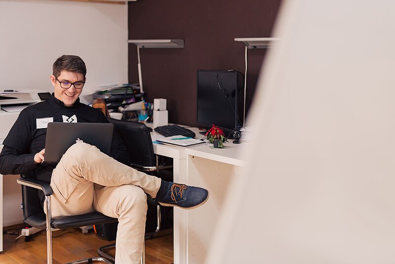 Mann mit Laptop vor Schreibtisch